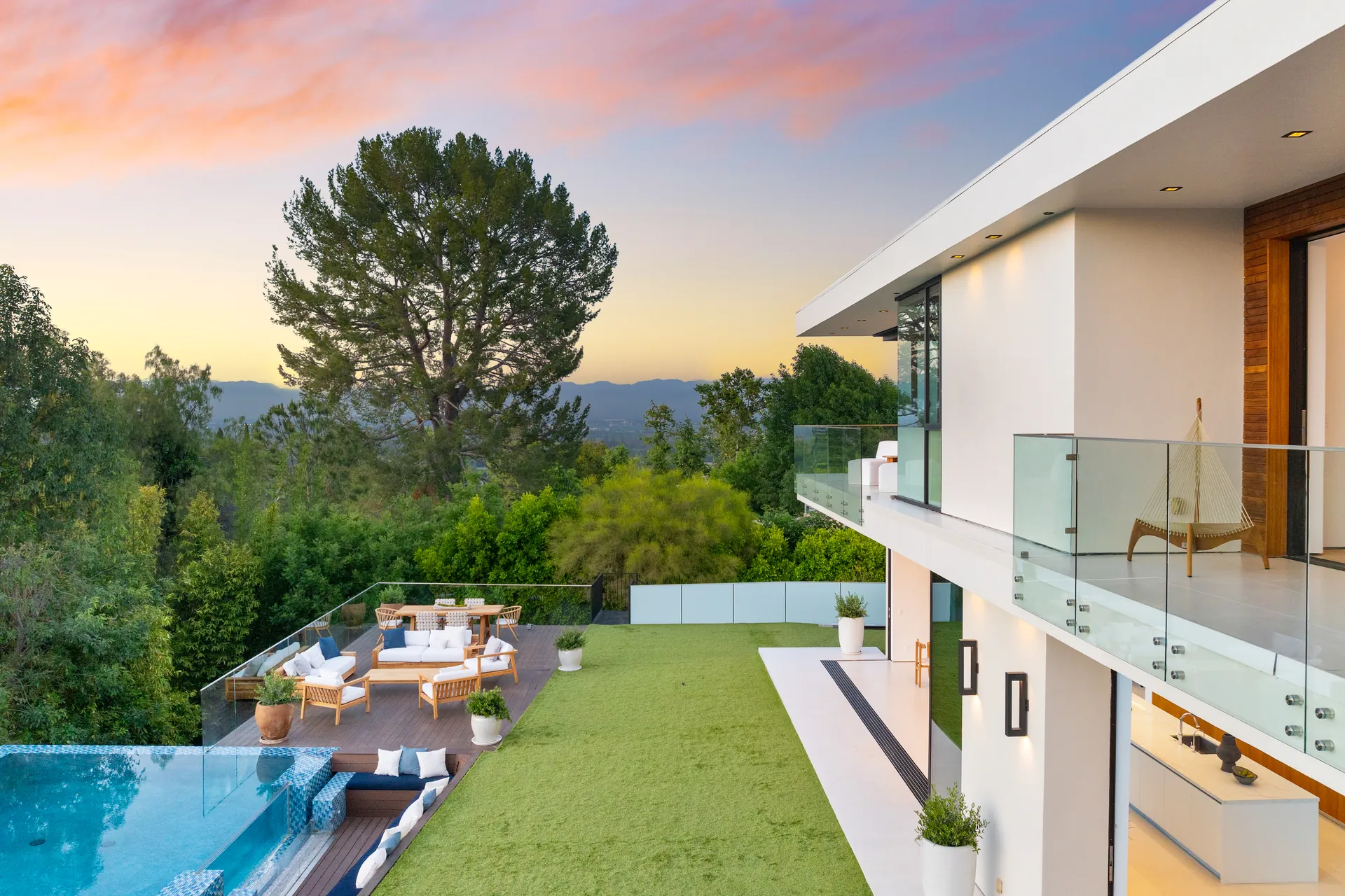 House with lawn, glass balustrade and infinity pool overlooking the landscape
