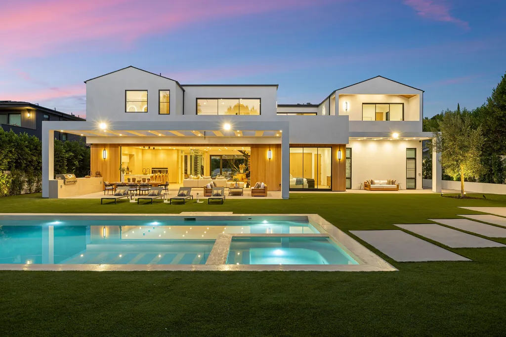 Luxury home with lit pool terrace at sunset