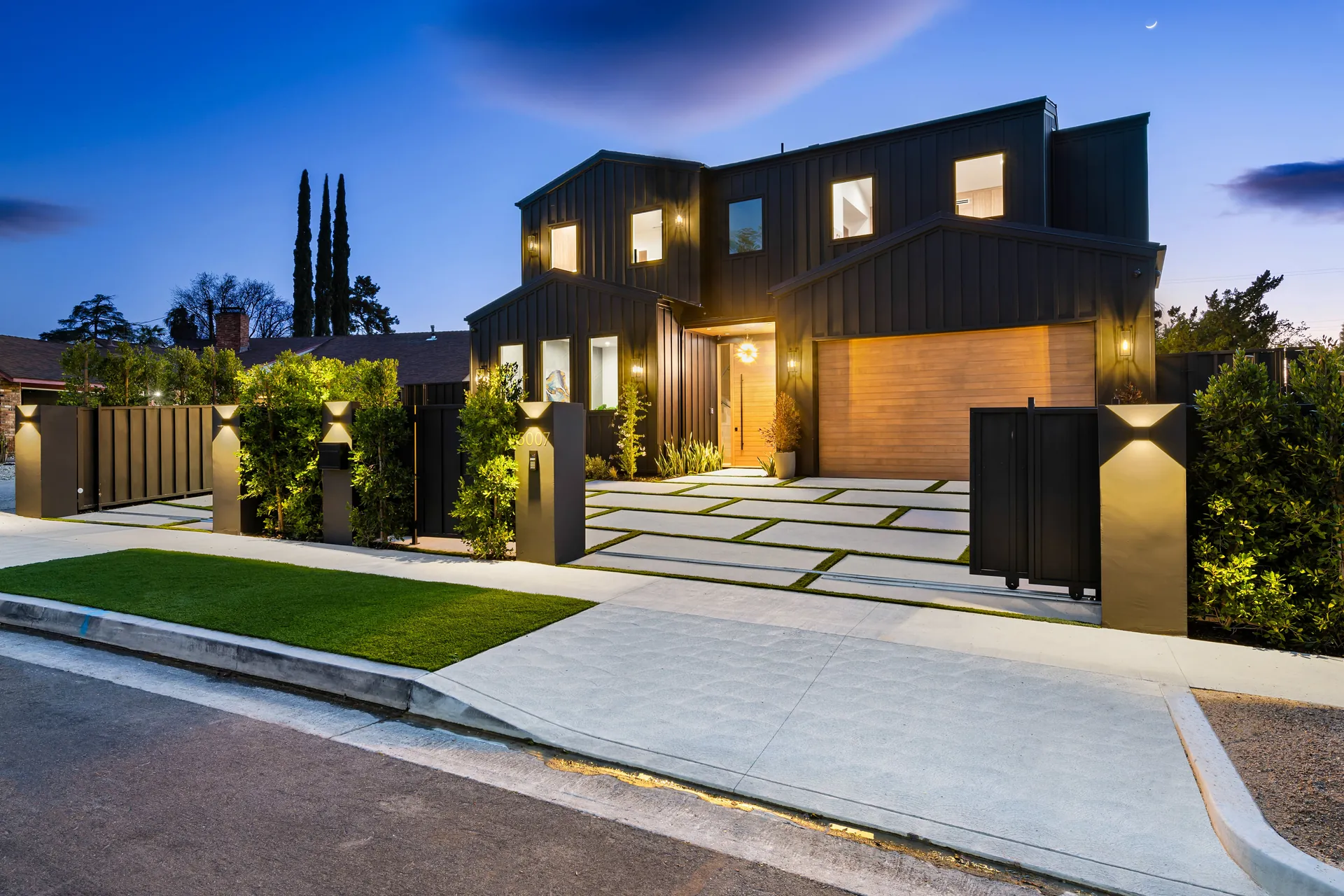 Modern home at night with layered garden lighting