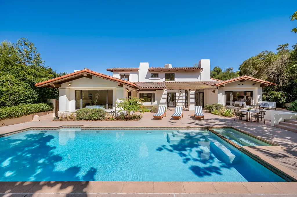 Mediterranean villa with a pool framed by lawn, palms and flowering shrubs